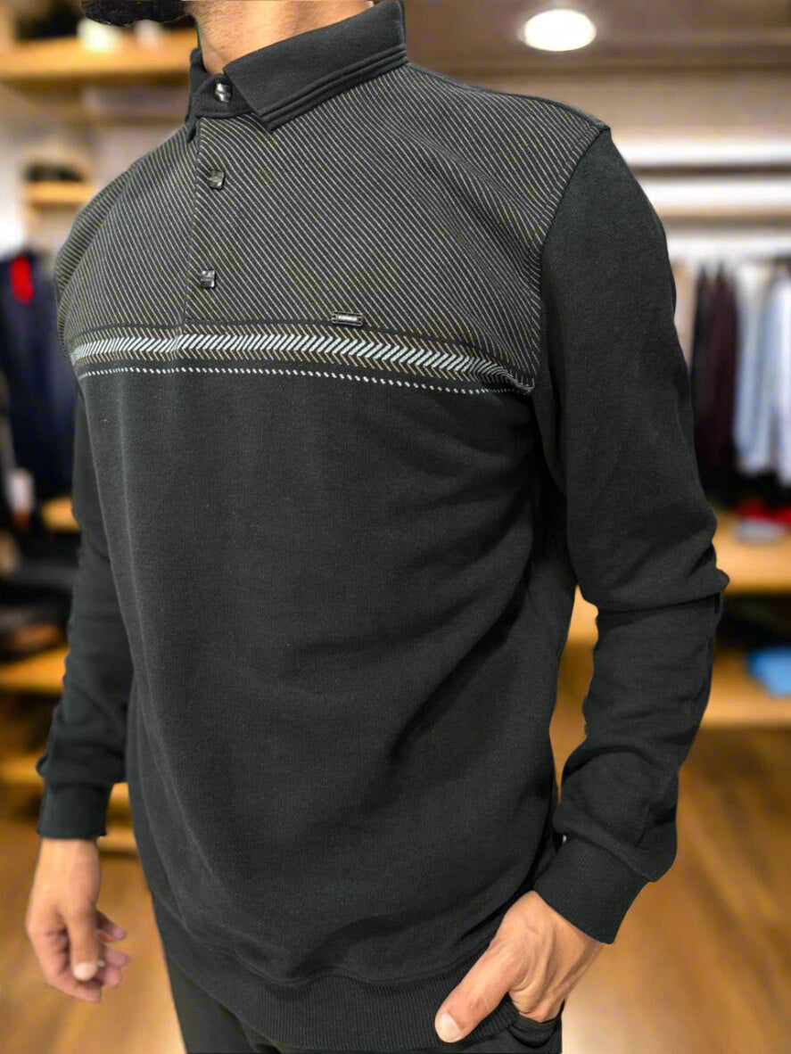 Man wearing a black and gray long-sleeve shirt with a patterned design in a clothing store.
